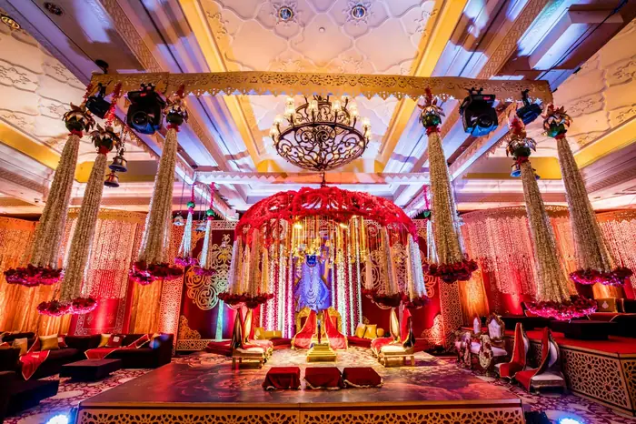 A lit sangeet stage under chandeliers